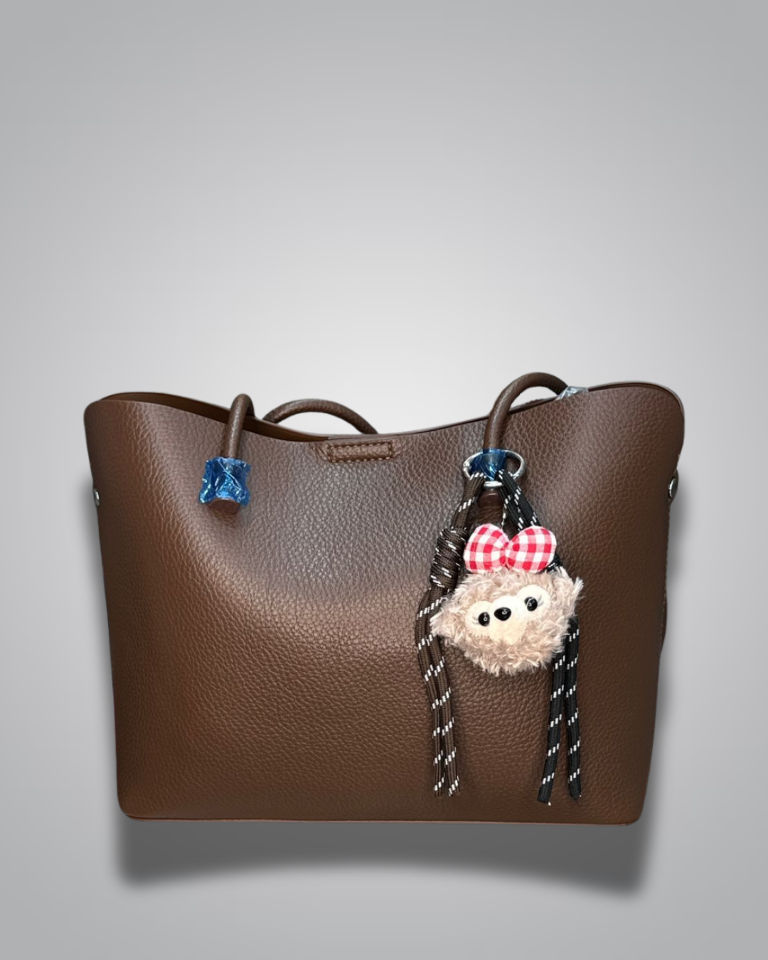 Beige handbag with a sloth keychain on a light gray background- Valentino Impex