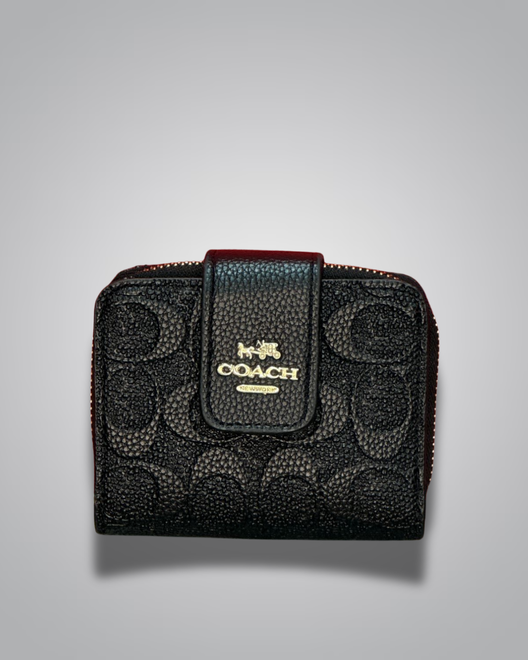 Black Coach wallet with gold logo on a gray background