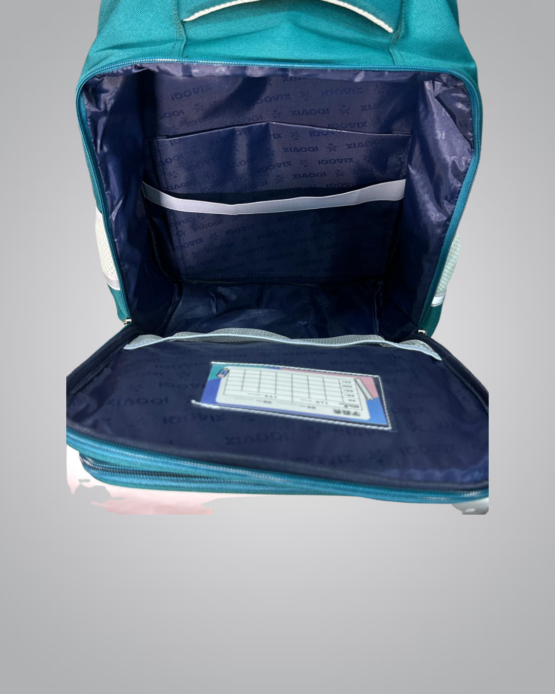 Open teal backpack with a blue interior and a small rectangular item on a gray background