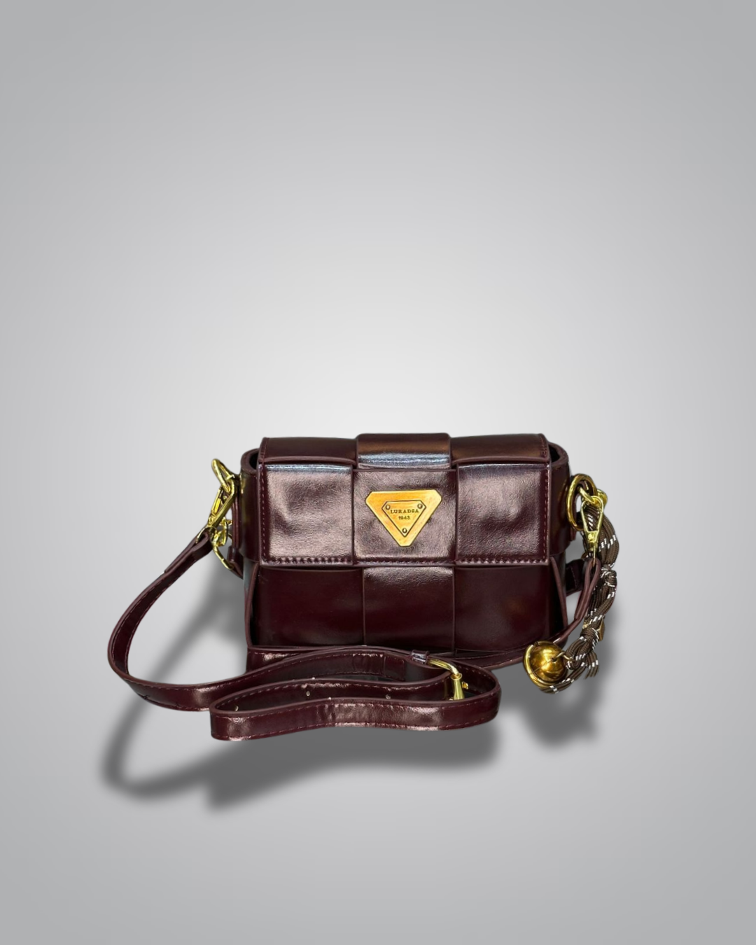 Brown leather handbag with gold accents on a gray background