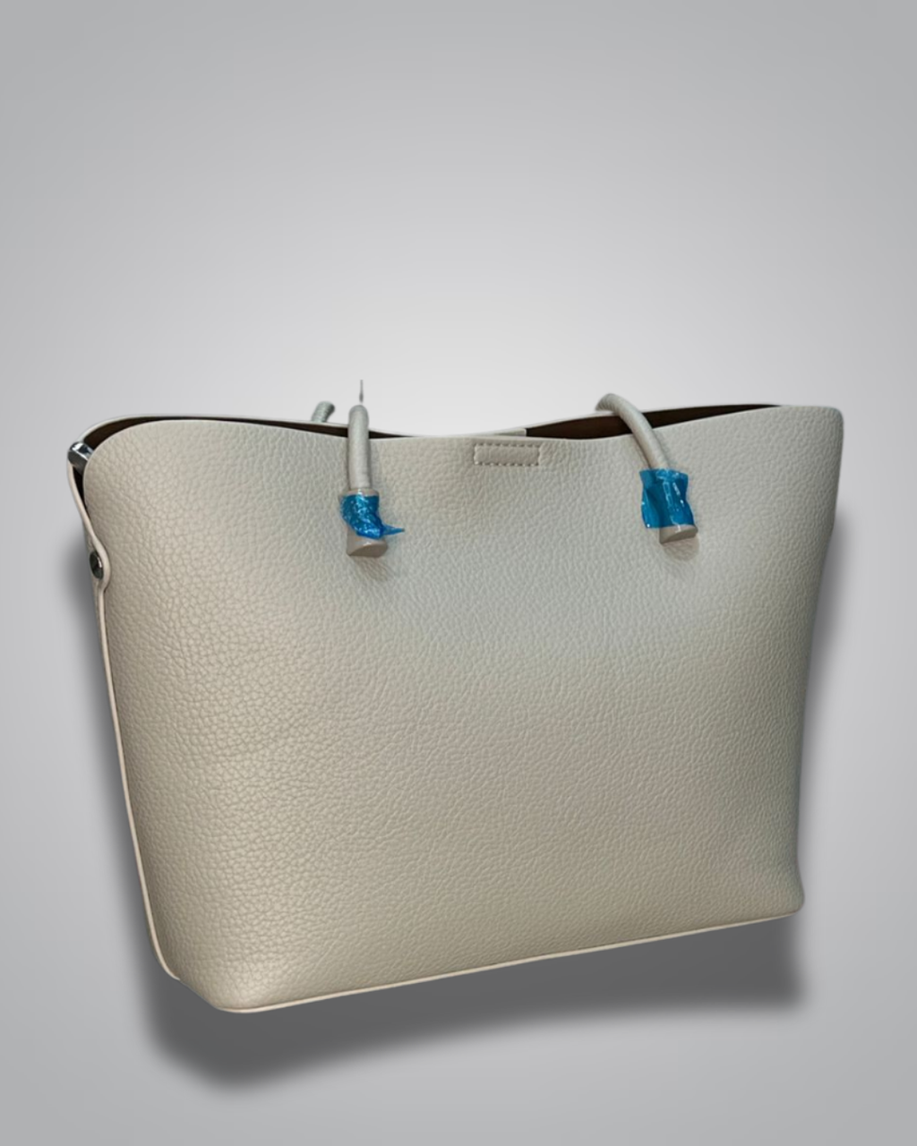 Beige handbag with a sloth keychain on a light gray background- Valentino Impex