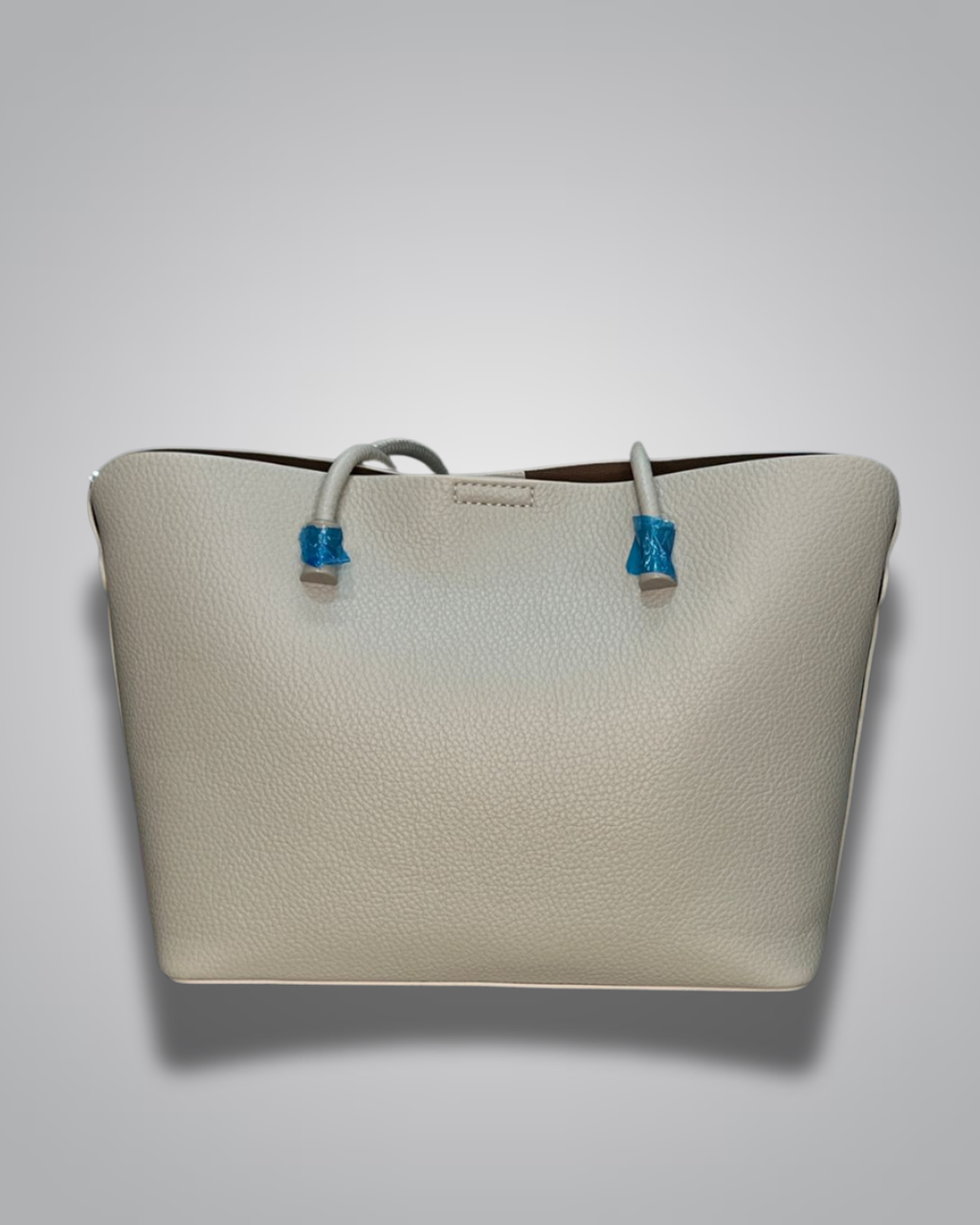 Beige handbag with a sloth keychain on a light gray background- Valentino Impex