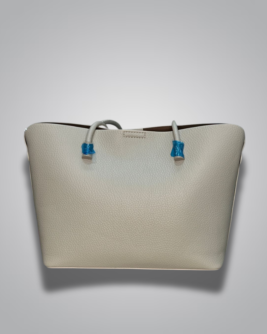 Beige handbag with a sloth keychain on a light gray background- Valentino Impex