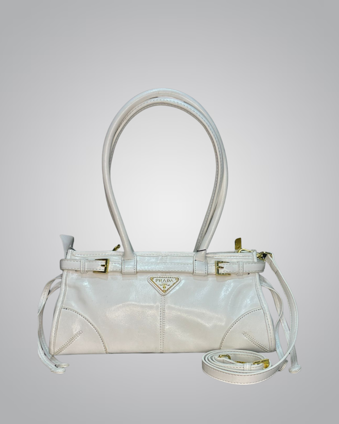 White handbag with gold accents on a light gray background
