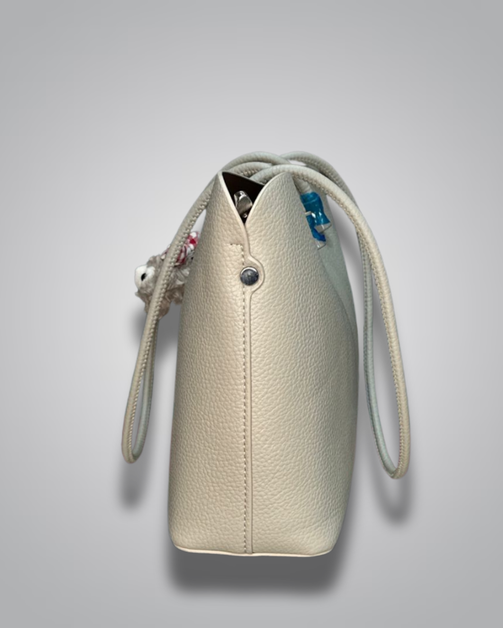 Beige handbag with a sloth keychain on a light gray background- Valentino Impex