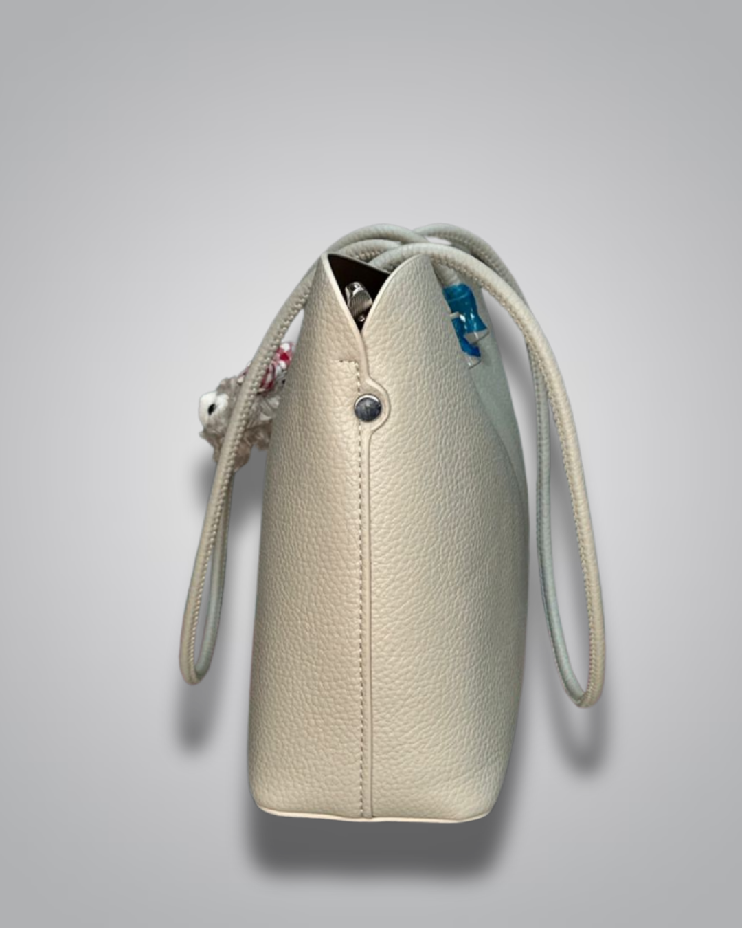 Beige handbag with a sloth keychain on a light gray background- Valentino Impex