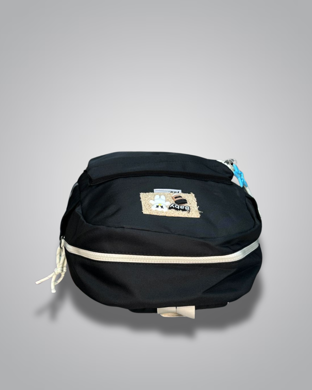 Black backpack with decorative patches and a blue star charm on a gray background- Valentino Impex