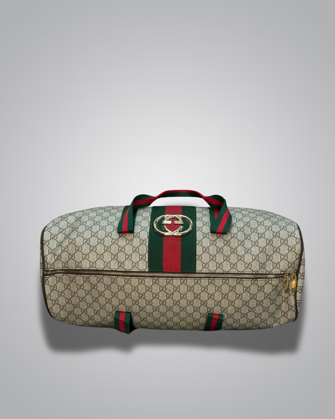 Gucci duffel bag with monogram pattern and green and red stripes on a gray background
